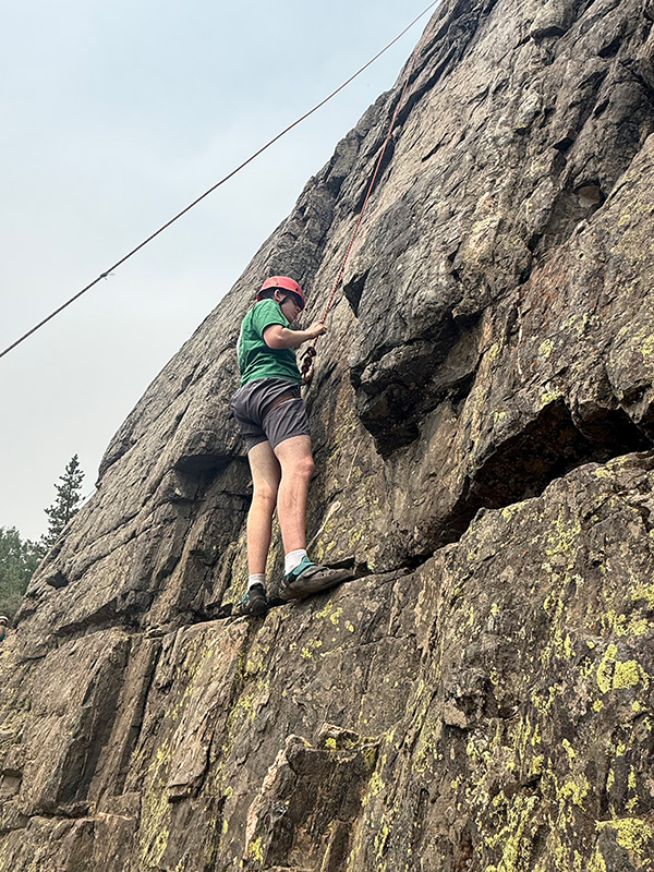 Boy standing on rock climbing wall ledge