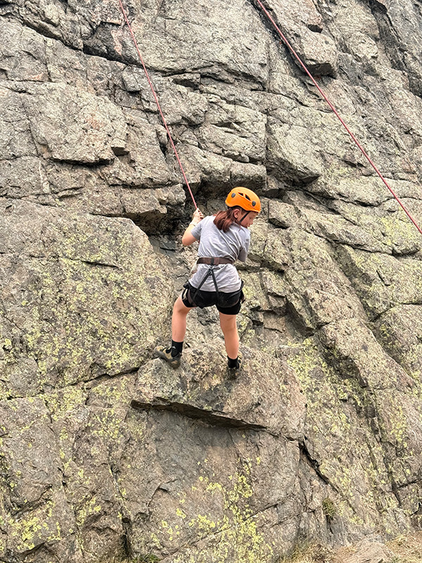 Young boy on rock climbing wall looking back towards ground