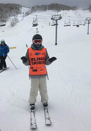 Ryan in ski gear with a bright orange "Blind Skier" vest