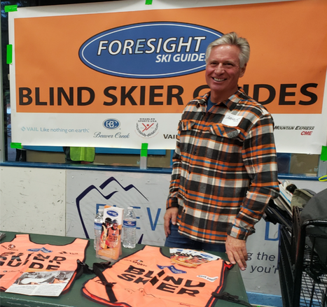 Greg Brozovich, Senior Guide, standing at a Foresight Ski Guides information table