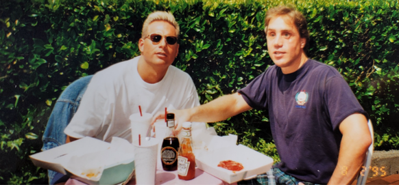 Greg and Peter sitting outside eating at a table