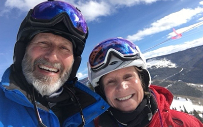 Mark and Jan Masto smiling at the camera wearing ski gear and helmets