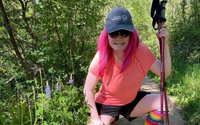 Jazmine in baseball cap, crouched and holding walking sticks