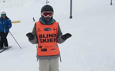 Ryan in ski gear with a bright orange "Blind Skier" vest