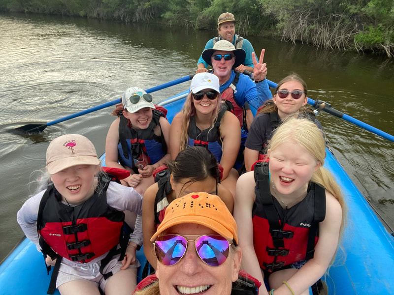 Smiling group of campers and guides on a raft on the river at summer camp.