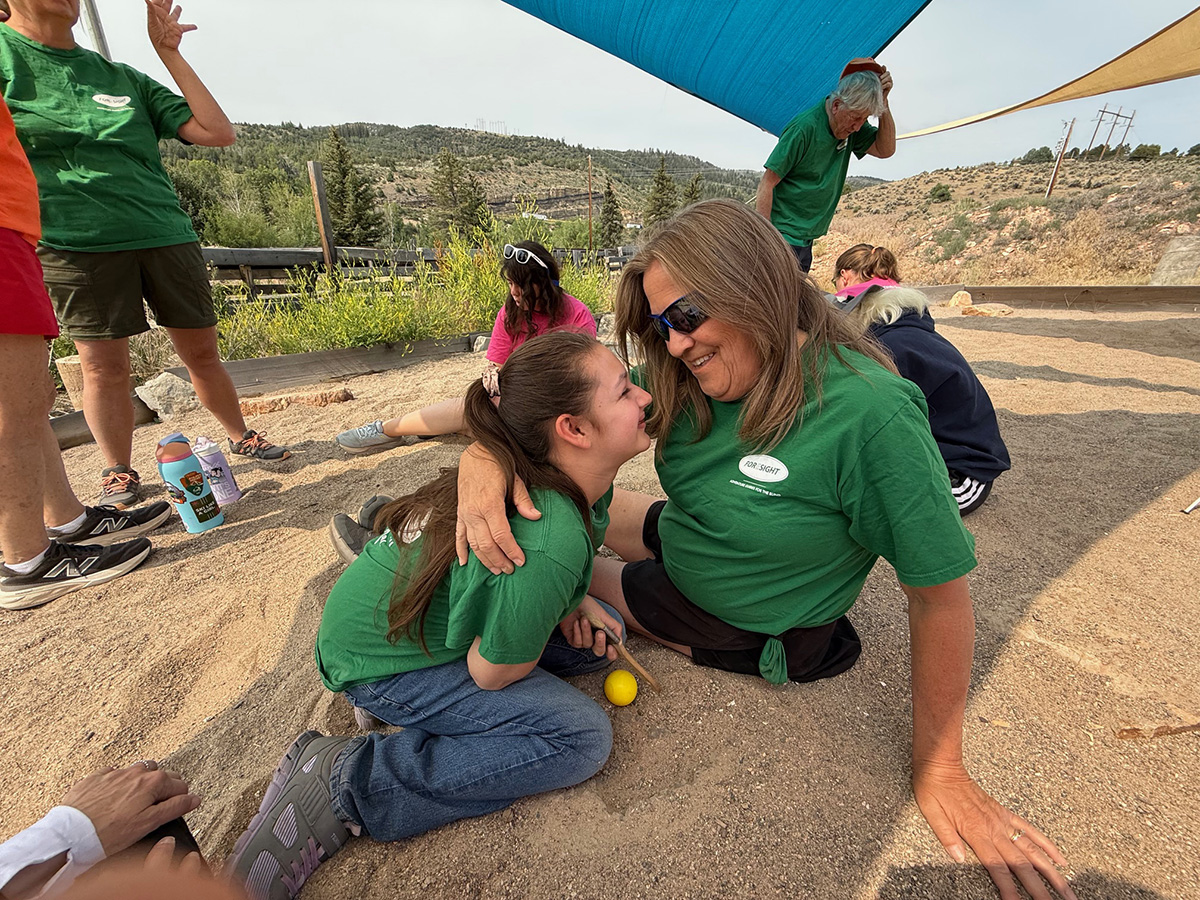 Camper and Guide hugging in dinosaur sand pit