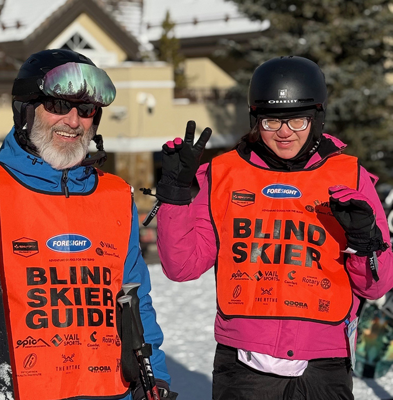 Guide posing with teen skier. Teen is giving thumbs up